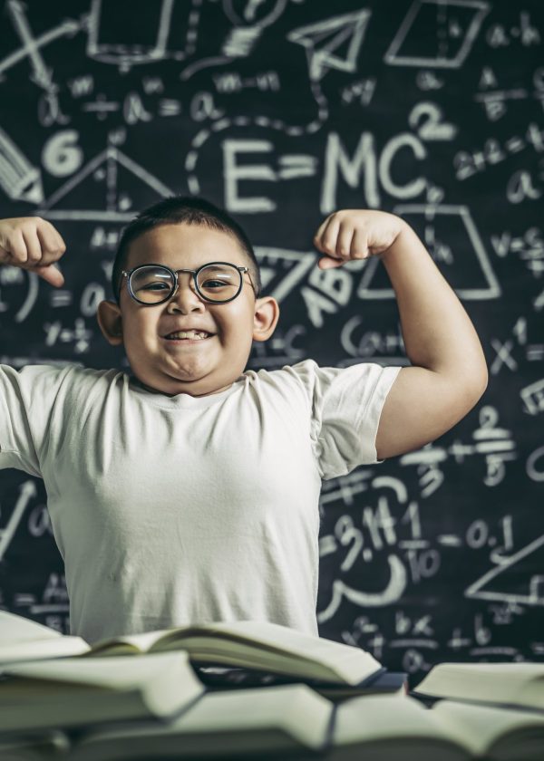 a boy with glasses sitting in the study and with both arms perpe
